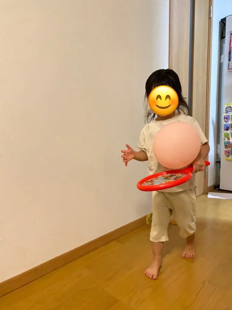 ラケットの上に風船をのせて歩いている子ども